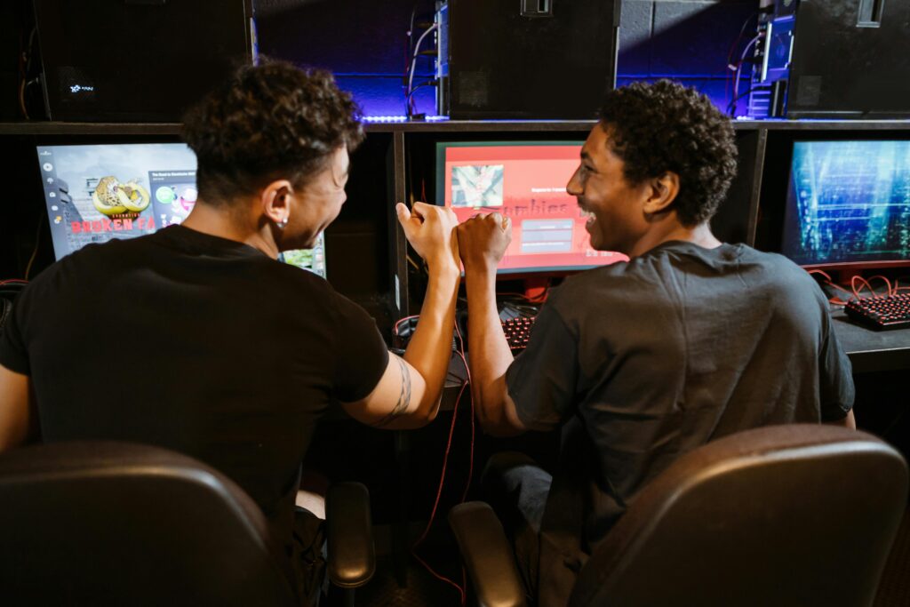 Two male friends enjoying a victory in a gaming competition indoors, showcasing teamwork and friendship.