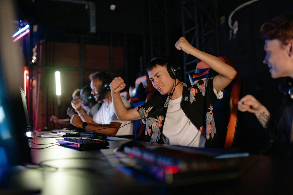 Excited gamers celebrating a win in a competitive gaming tournament with headphones.