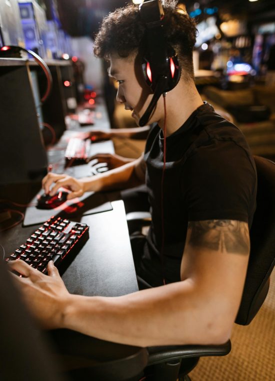 A gamer wearing headphones intensely focused on gaming in a cyber-themed arcade.