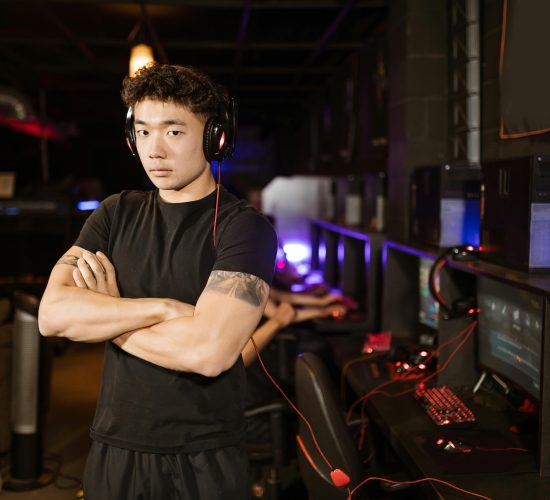 A confident gamer stands in a modern eSports arena, showcasing the gaming environment.
