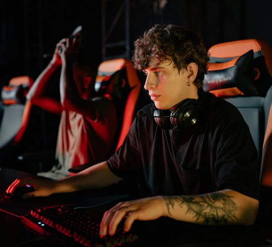 Competitive gamers in an esports tournament concentrating deeply in dimly lit setting.